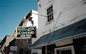 Bluff Mountain Outfitters sign being hung by a man in an extension truck basket.