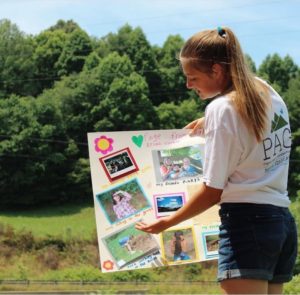 A girl presenting a postboard with photographs